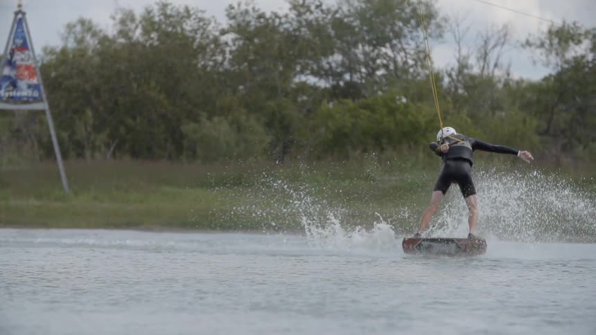A white person performs a jump while water skiing on a lake