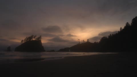 Clouds move over a sandy beach and rock formations
