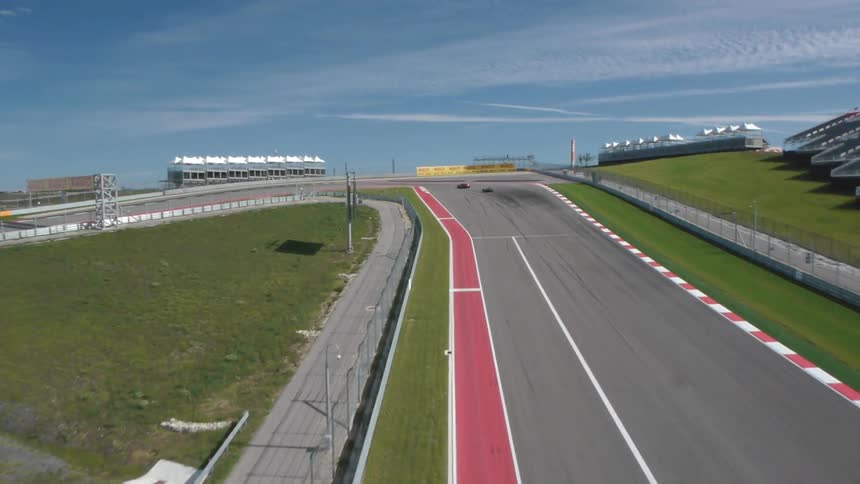 Two race cars enter a track and turn a sharp corner