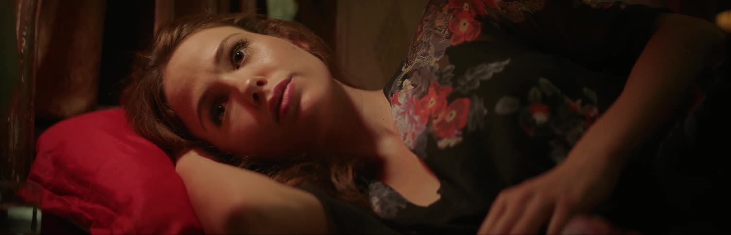 A woman is lying on a bed and speaking at night