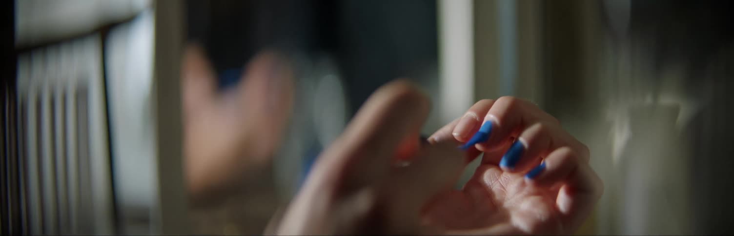 Person painting their fingernail with blue nail polish
