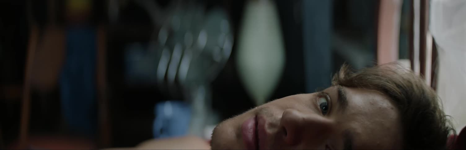 A man is laying down looking to his side then forward