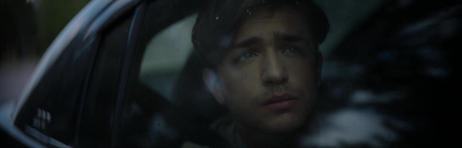 A man looking out a car window as it drives down a road