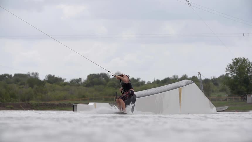 A wakeboarder sliding off a ramp into the water