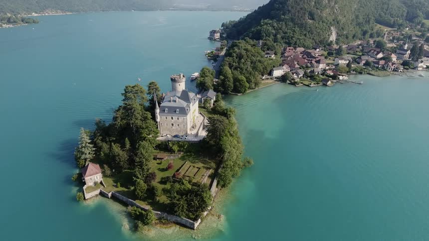 A mansion with a turret sits on a tree covered peninsula