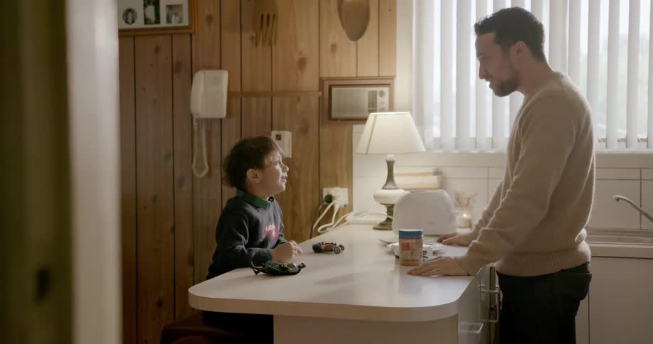 A man talks with his child in the kitchen on a sunny day
