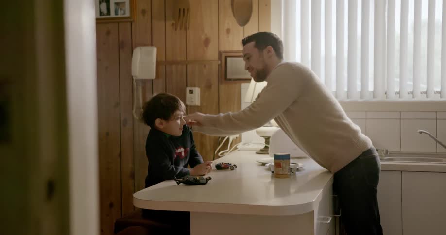 A man talks with his child and adjusts his shirt for him