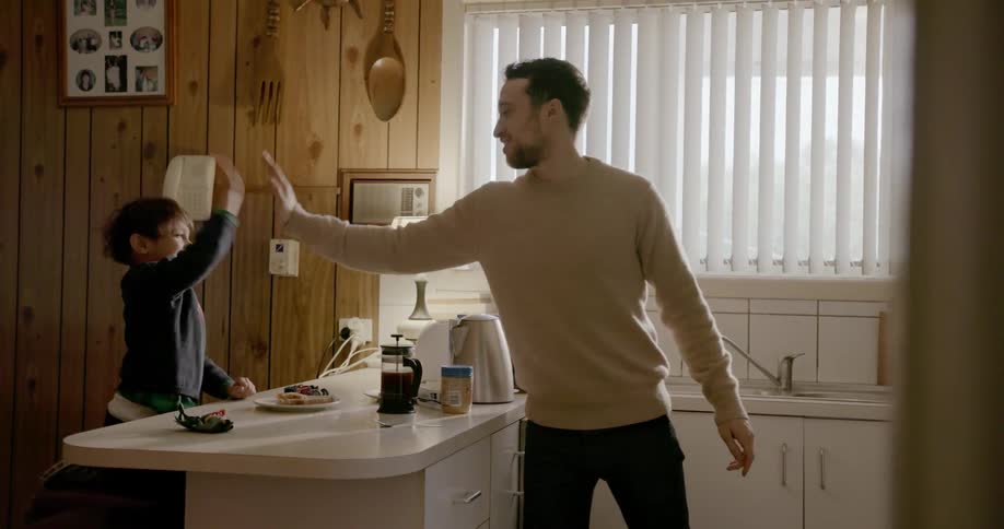 A man and boy high five in the kitchen