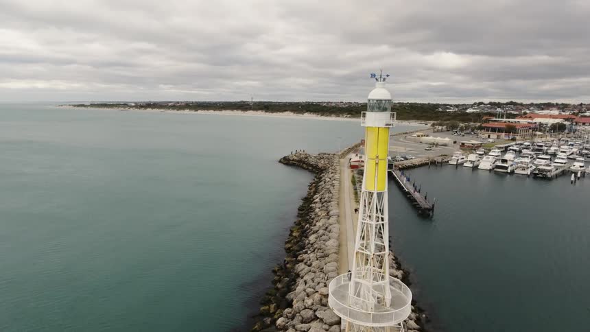 A lighthouse stands tall at the end of a rock island