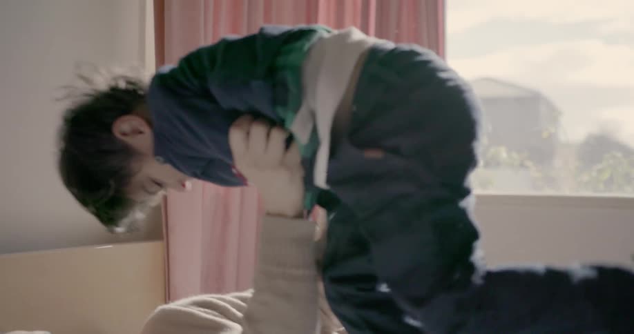 Man wrestles with young boy in bed