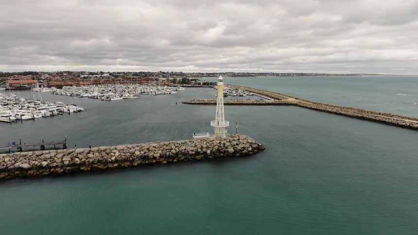 A lighthouse sits at the end of a inlet
