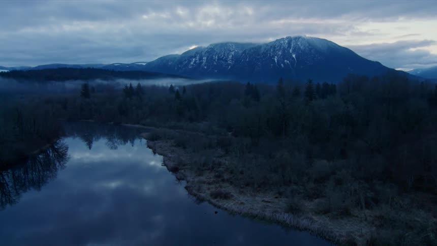 Foggy lake and mountain surrounded by forest