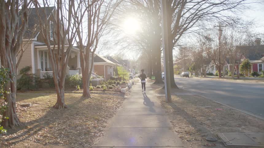A woman is jogging down the sidewalk