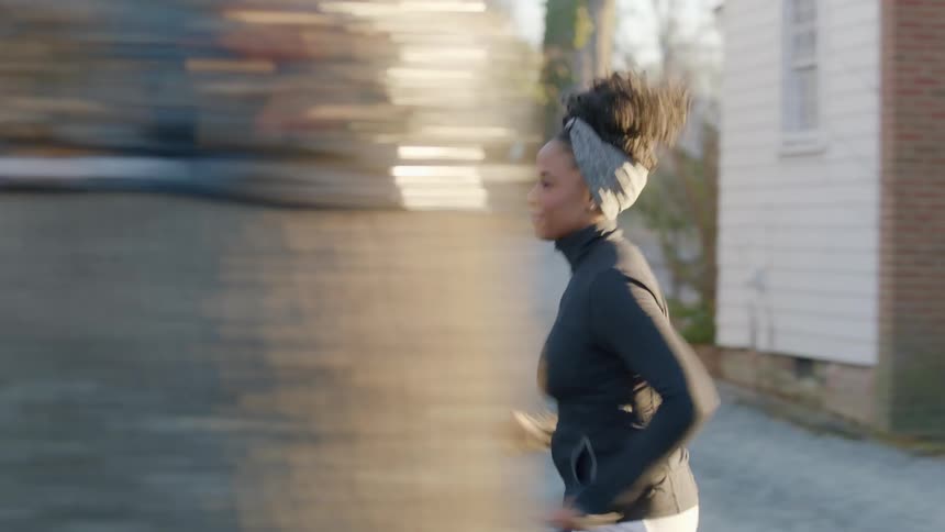 A black woman jogs in place before taking off outside