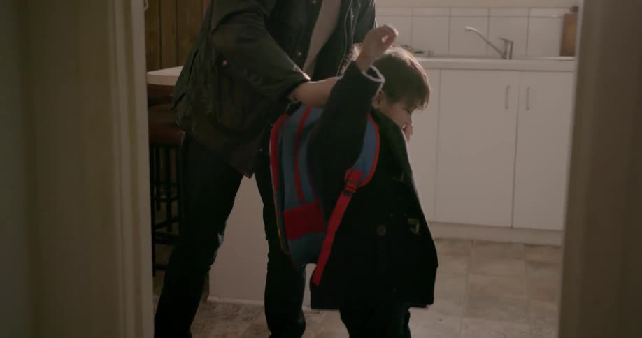 Dad puts backpack on son as they head out the door