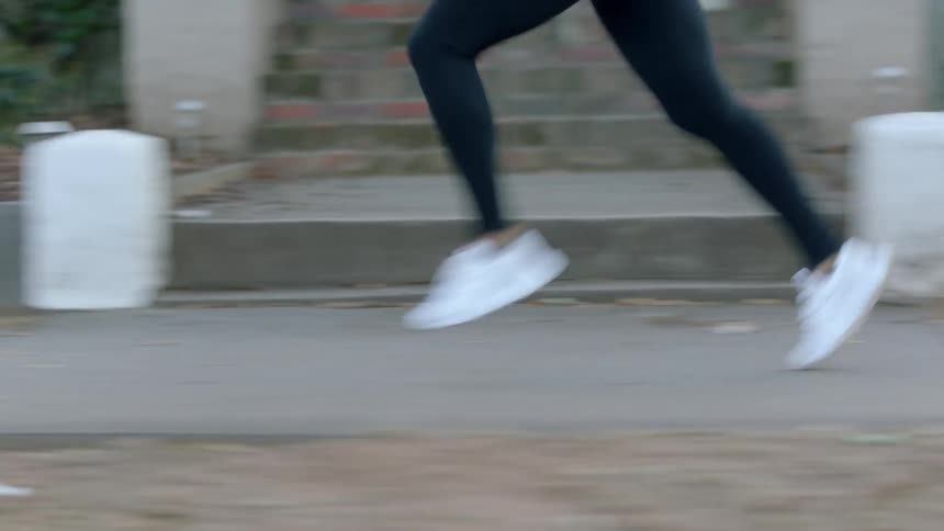 A person is running on the sidewalk of a town