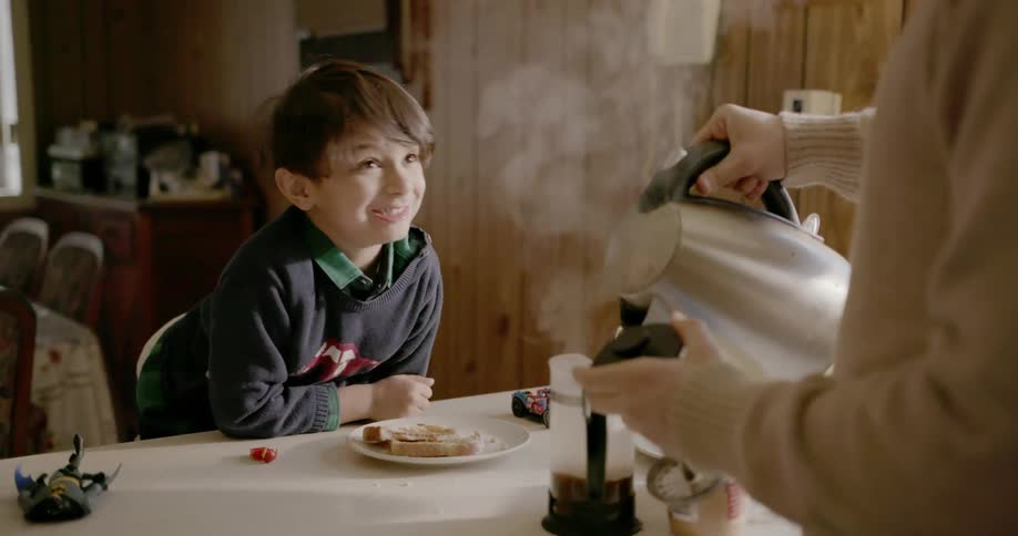 A child eats as a person pours some coffee