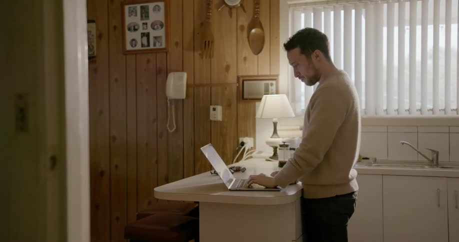 Man using laptop on kitchen counter at home