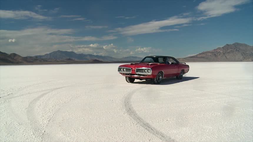A sports car performs donuts in the sand