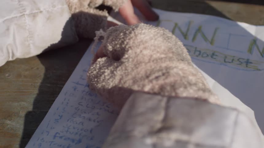 A person wearing gloves is marking something off a list