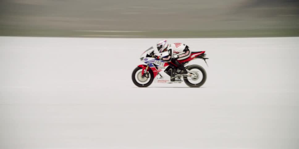 A man is racing his motorcycle in the desert