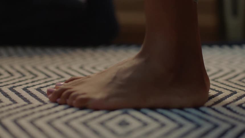A woman places her feet down on a rug