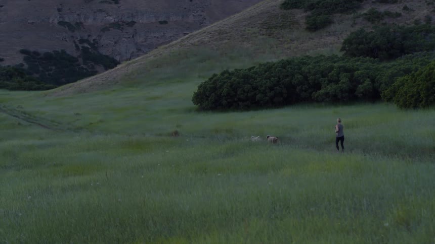 A woman is running with her dogs ahead of her