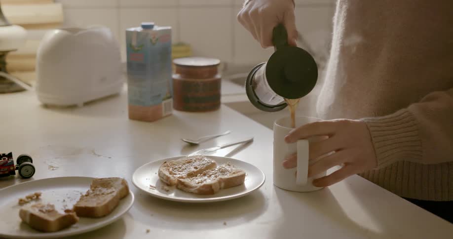 A person pours coffee into a white mug