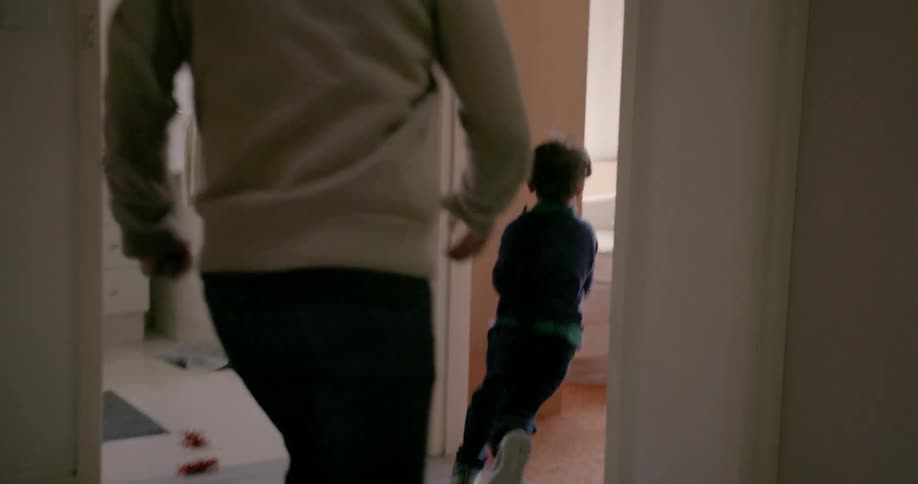 A kid is running through a house with the parent chasing them