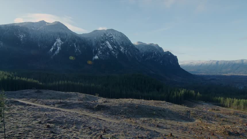 The sun shines on a valley between snowy mountains