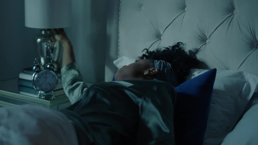 A woman wakes up and turns a lamp on