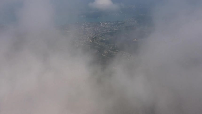 Mountainside and city emerge through the clouds 