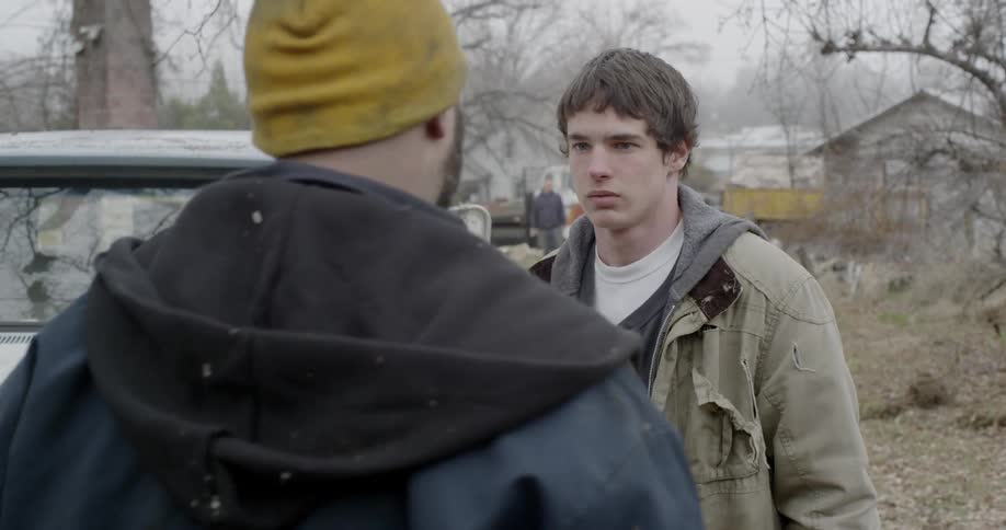 A man confronts a young man outside by a pickup truck