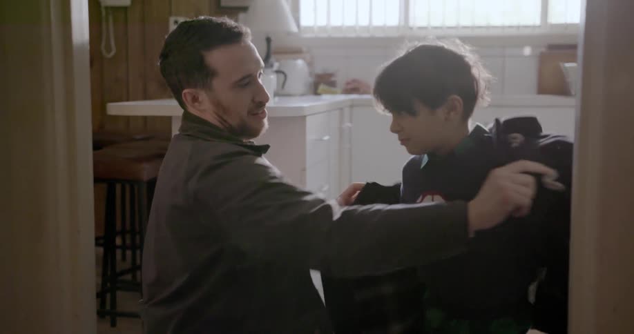 Man puts a coat on a child and child ducks out of it laughing