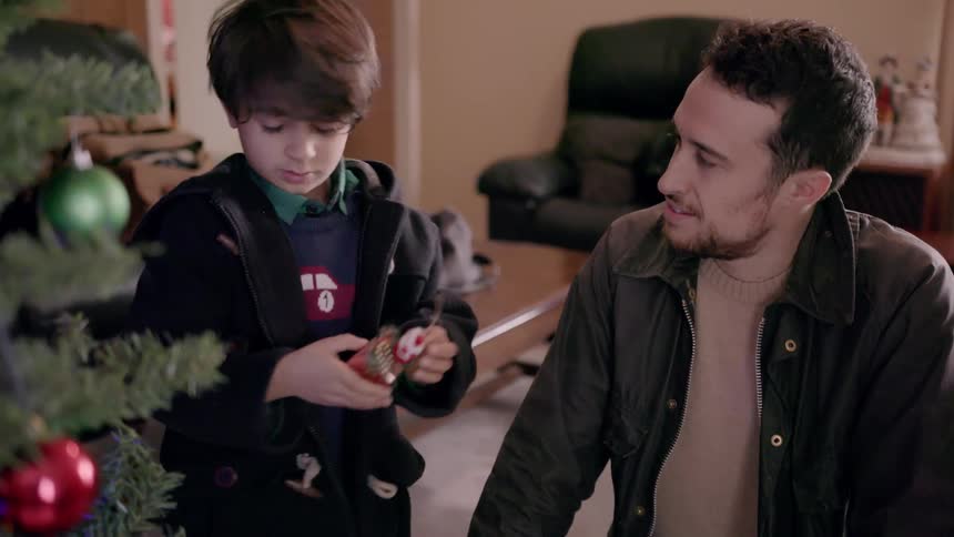 Father and son putting ornaments on Christmas tree