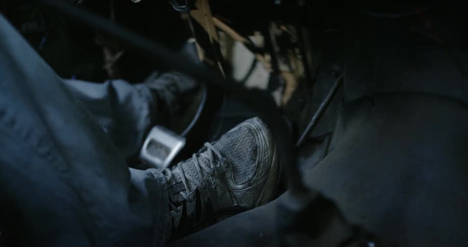 Person's feet stepping on pedal in a car footwell 