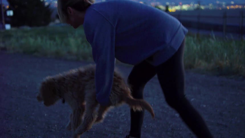 Woman puts dog on the ground as she's walking on path