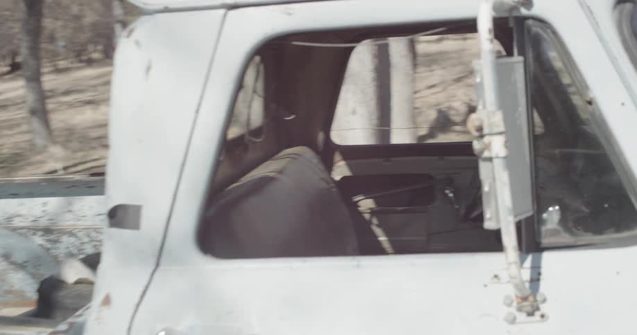 A man grabs a baseball bat and throws it in the back of a pickup truck and then gets in and starts it
