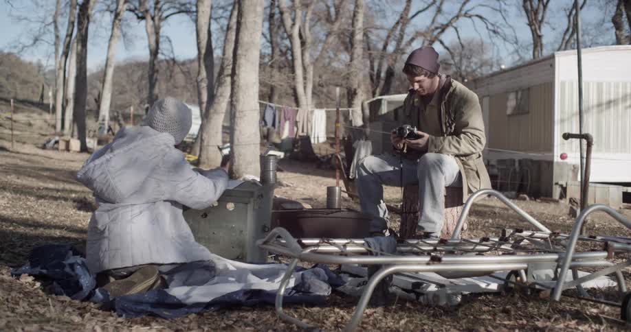 A man and woman sit outside of a trailer
