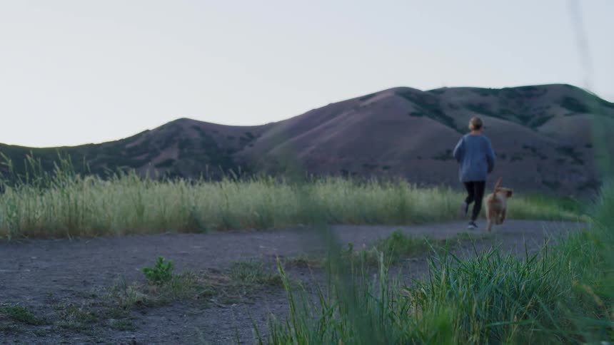 A woman jogs outside with her dog
