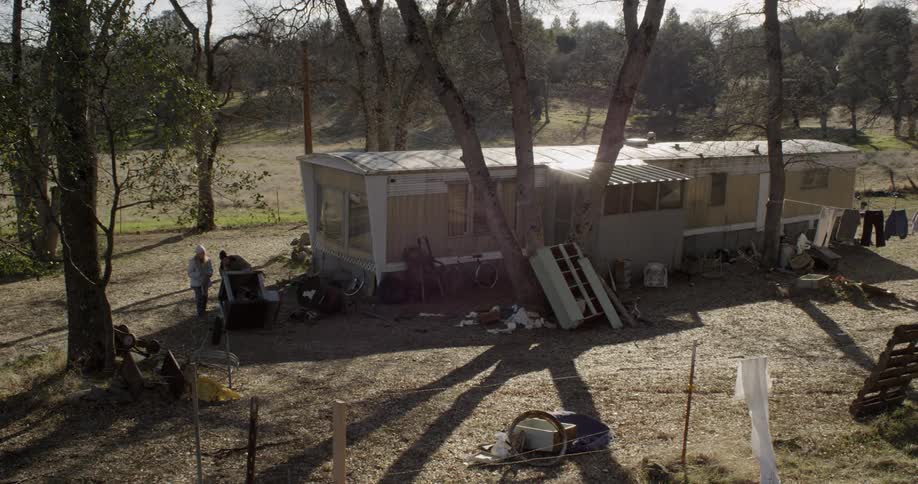 A man and woman sit outside of a trailer