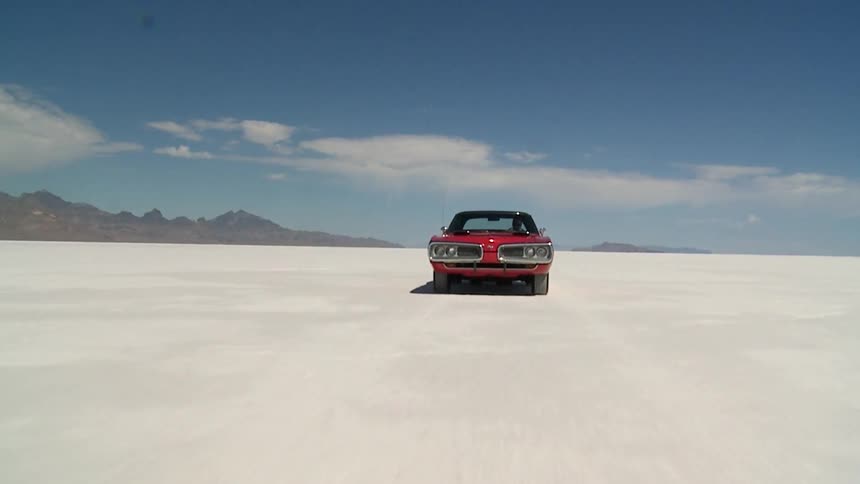 A car is driving across the salt flats