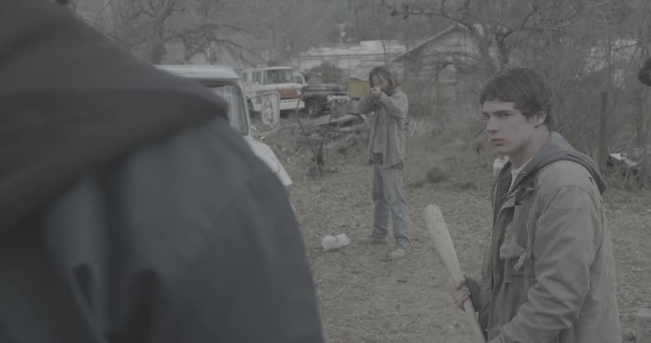 A man points a gun at a bat wielding man