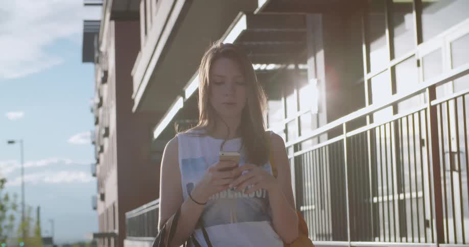 A young woman stands outside using her phone