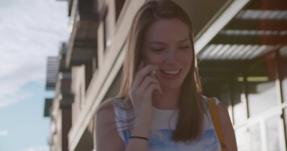 A woman walks on the sidewalk talking on the phone