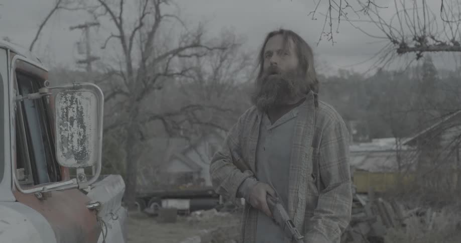 A man angrily carries and cocks a shotgun