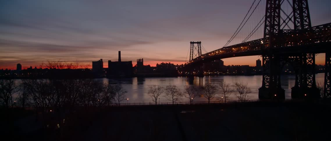 A city bridge spans a river at dusk