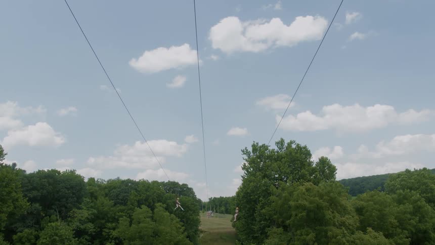 Three people ride a zip line