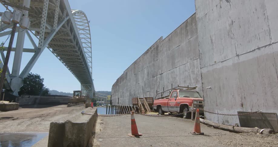 Truck sits near a long bridge under a blue sky