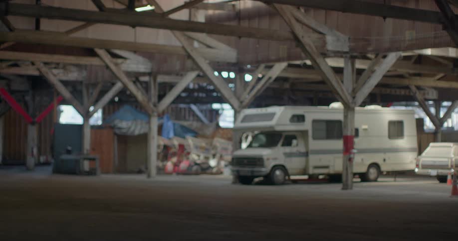 Vehicles sit parked in a large out building